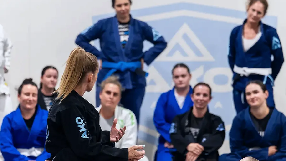 A women's class listening to a coach on the mats at Ako Martial Arts