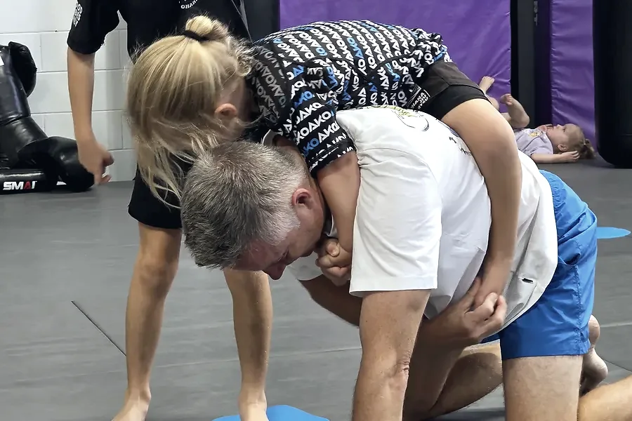 A dad in his gi training on the mats with his kids at Ako Martial Arts