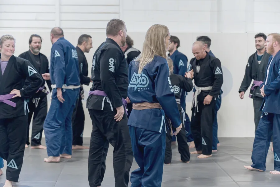 An adults BJJ class at Ako Martial Arts, men and women of mixed ages and belts standing together in their gis
