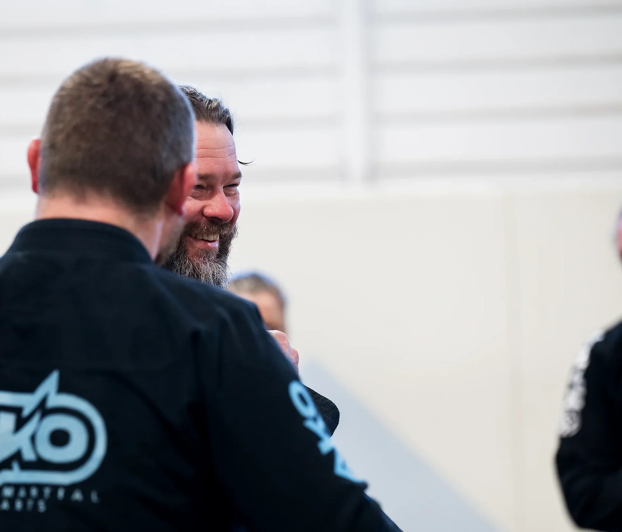 Two Ako Martial Arts coaches sharing a laugh on the mats in Sandgate